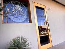 アースカラーの外壁と木製のドア『BILDA』のネオンのロゴが目印!