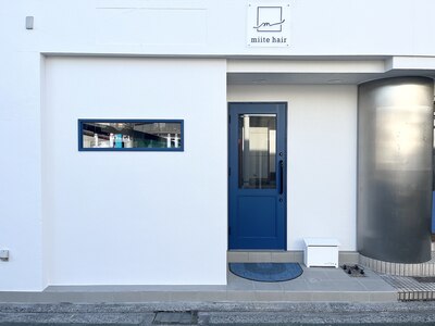 白の外観に紺色のドアが目印の美容室となります。