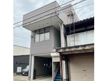 グレーの建物 右の階段から2階へお願いします