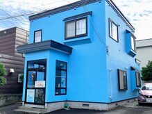 住宅街の中にあるひときわ青い建物です。お車はピンクの車の前に