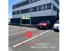 駐車場は建物西側の南から2番目、赤い車の前になります。