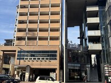 国体道路沿い、ロンハーマンカフェの向かいの茶色い建物（左）